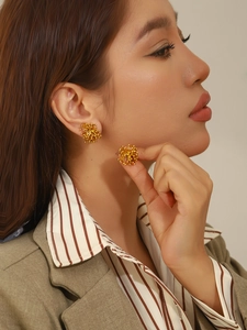 Gros plan de boucles d'oreilles fleurs en acier inoxydable doré sur un mannequin