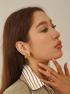 Vue détaillée de boucles d'oreilles dorées en forme de fleur portées par un mannequin