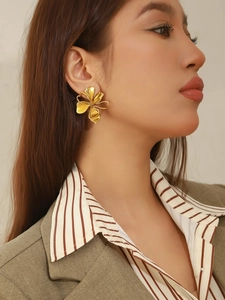 Gros plan d'une grande boucle d'oreille fleur dorée sur un mannequin au style vintage