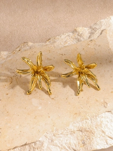 Détail macro de boucles d'oreilles fleur dorées avec texture en métal brossé