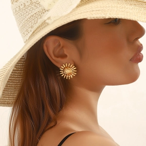 Detalle de pendiente de botón con forma de sol dorado vintage para un look de verano