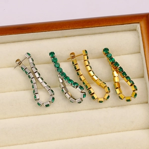 Dettaglio degli orecchini a catena dorati e argentati con strass verde smeraldo