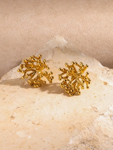 Détail de boucles d'oreilles dorées en forme de corail avec textures organiques