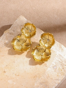 Vue détaillée des boucles d'oreilles fleurs dorées avec zircons blancs sur une pierre