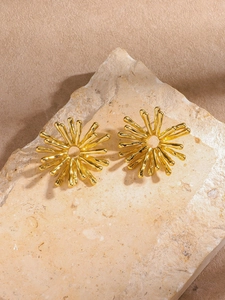 Vue détaillée de boucles d'oreilles tournesol dorées sur un fond de pierre naturelle texturée