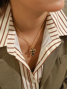 Detailed view of vintage gold ball chain with black enamel cross pendant and crystals
