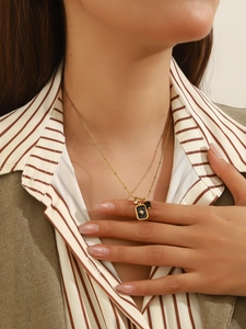 Detail of a gold-plated beaded necklace with a black rectangular starburst pendant