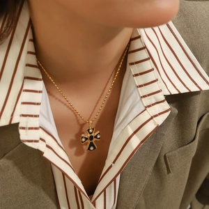Gothic cross pendant necklace with black enamel and gold bead chain on female model