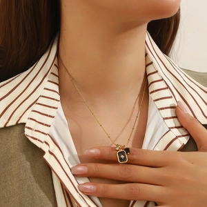 Gold stainless steel necklace with black rectangular starburst pendant and crystal charm
