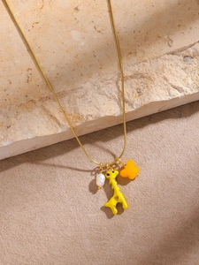 Detailed shot of giraffe pendant necklace with pearl and floral charms on a stone base