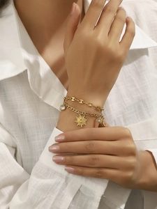 Détail du bracelet double couche plaqué or avec breloques soleil, lune et cœur au poignet