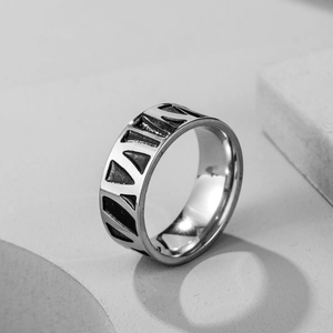 Macro shot of silver stainless steel ring featuring black geometric triangle engravings