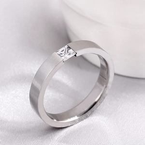 Makroansicht des matten Edelstahlrings mit quadratischem Kristall auf Satin-Hintergrund