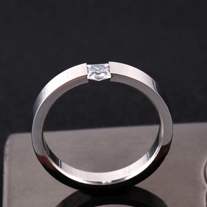 Makrodetail eines gebürsteten Edelstahlrings mit quadratischem Diamant und poliertem Rand