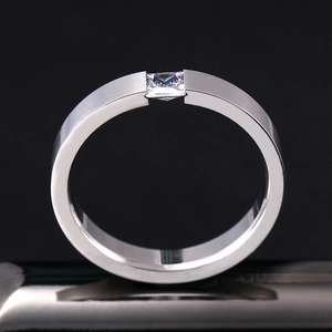 Makroaufnahme von gebürstetem Edelstahlring mit quadratischem Diamant auf schwarzem Grund
