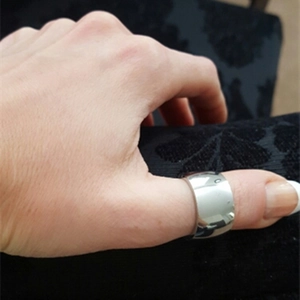 Detailaufnahme des 12mm breiten silbernen Edelstahlrings am Daumen auf schwarzem Stoff