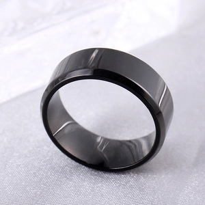 Close-up of a polished black titanium steel ring with double beveled edges and glossy finish