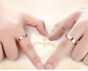 Close-up of two-tone stainless steel couple rings held in a romantic heart hand gesture