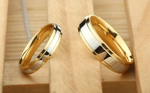 Macro shot of two-tone gold and silver couple rings on a warm wooden background