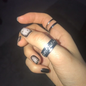 Close-up of a silver spinning chain ring on thumb with minimalist band rings set