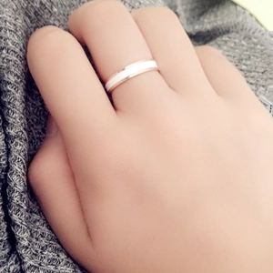 Minimalist rose gold ring with white ceramic inlay shown worn on a hand over gray fabric