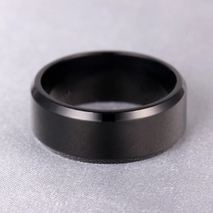 Detail of a minimalist black titanium ring with smooth matte finish and polished edges