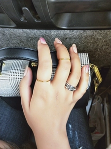 Detail shot of silver chain pattern ring and gold minimalist bands on model fingers