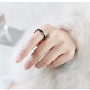 Minimalist black ceramic ring with rose gold edges worn on index finger for women and men