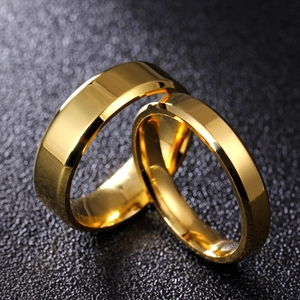 Close-up of polished gold titanium steel rings with double beveled edges on dark background