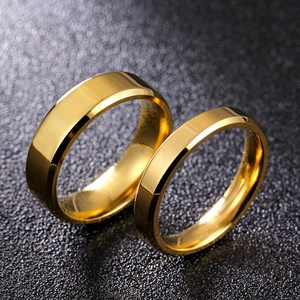 Detail of two polished 8mm gold beveled edge titanium steel rings on dark background