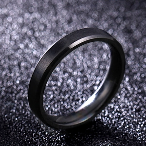 Macro shot of 8mm black brushed tungsten ring with polished beveled edges on dark bokeh background