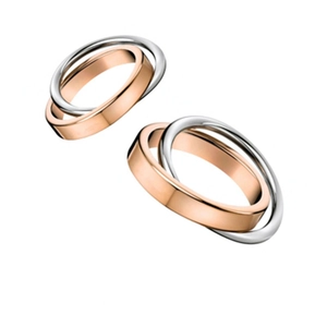 Macro detail of interlocking rose gold and silver stainless steel rings with polished finish