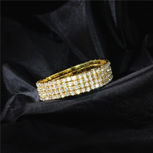 Macro shot of gold elastic bracelet with four rows of sparkling crystals on black silk