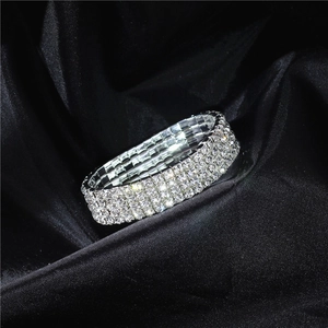 Macro detail of elastic four-row silver rhinestone bracelet on black satin background