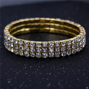 Close-up of triple-row sparkling crystal rhinestones on a golden elastic bridal bracelet