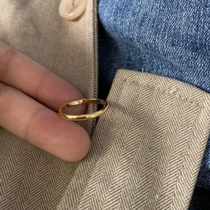 Primo piano di un anello in acciaio dorato lucido minimalista su sfondi in tessuto testurizzato