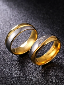 Vue macro de bagues de couple bicolores en acier inoxydable avec cristaux sur fond sombre