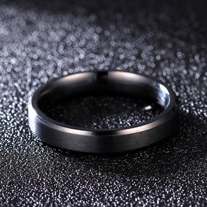 Macro shot of matte black beveled edge titanium ring with brushed metal texture finish