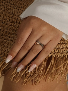 Detail of minimalist two-tone intertwined ring in silver and rose gold on a hand