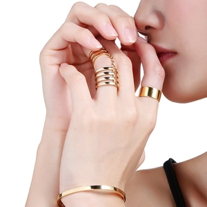 Polished 10mm wide gold ring stack and layered chain ring set on hand macro view