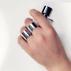 Polished silver 18mm wide stainless steel rings held by a hand on a minimal background