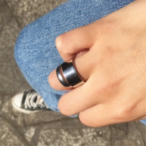 Polished silver 10mm wide flat band ring shown worn on finger in an outdoor setting