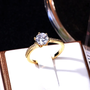 Macro detail of a six-prong set round zircon ring with a pavé band on a white cushion