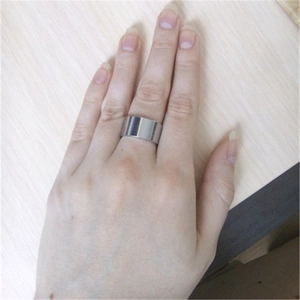 Macro shot of a 10mm wide silver stainless steel flat ring worn on finger on wooden background