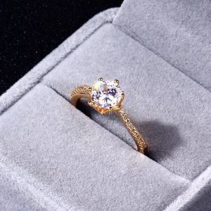 Macro detail of a classic gold ring with round cut zircon set in grey velvet jewelry box