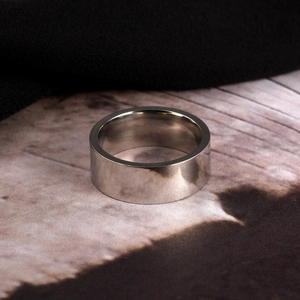 Detailed close-up of 8mm wide polished stainless steel ring on a dark textured background