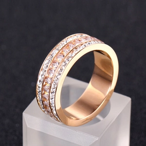 Gros plan détaillé sur une bague large en or rose avec trois rangées de zircons brillants