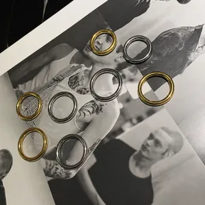 Anillos minimalistas de oro y plata pulidos presentados sobre un libro de moda vintage