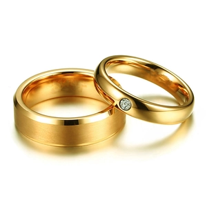 Primer plano de anillos de pareja de acero de titanio dorado con acabado cepillado