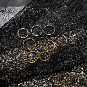 Anillos minimalistas de acero inoxidable dorado y plateado sobre fondo negro texturizado